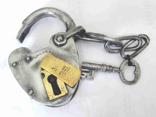 fig 1. An antique heart-shaped steel railway padlock featuring a stamped brass keyhole cover, attached chain, and matching iron key.