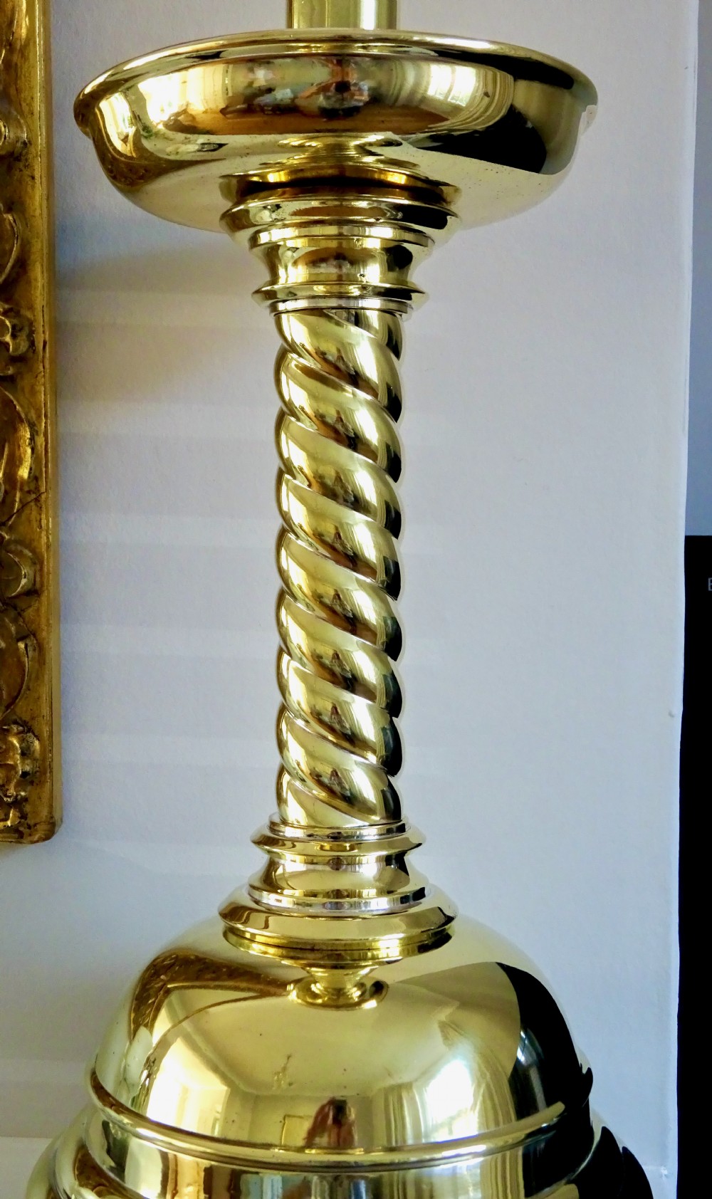 A pair of polished brass candlesticks with barley twist stems, broad drip pans, and domed bases set on small ball feet. View II