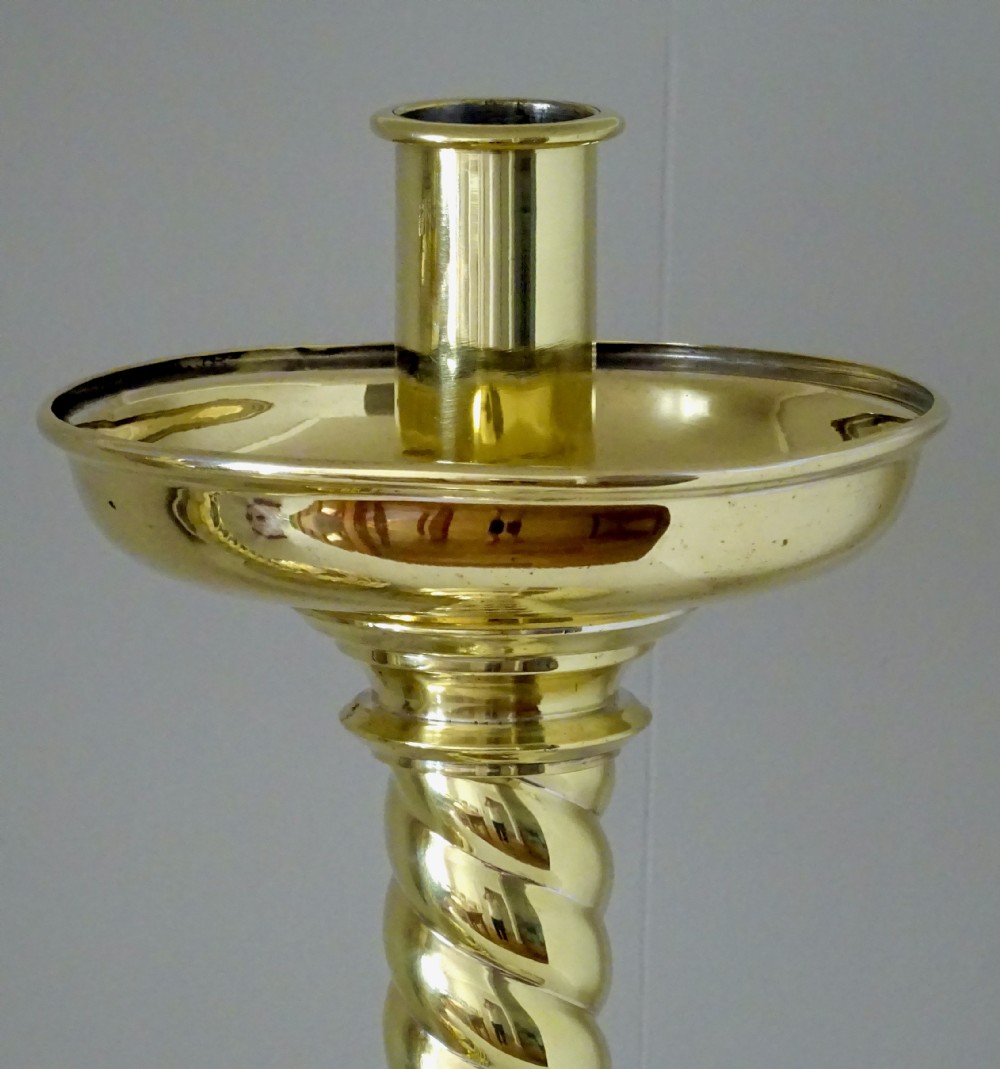 A pair of polished brass candlesticks with barley twist stems, broad drip pans, and domed bases set on small ball feet. View IV