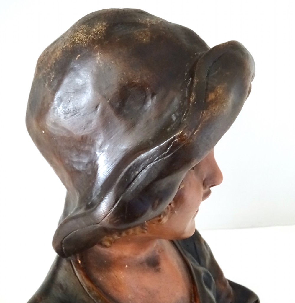 A 1930s French polychrome plaster bust depicting a young child wearing a hat, set upon a dark rectangular plinth with scrolled corners. View VIII