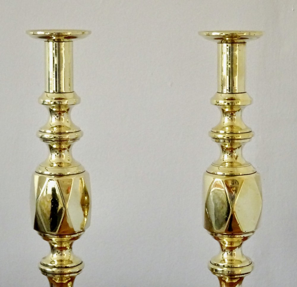 A pair of polished Victorian brass candlesticks with turned columns, faceted central knops, and square bases with cut corners. View IV