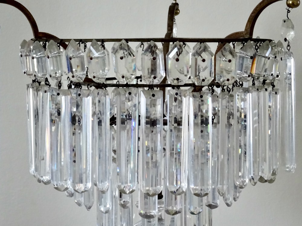 An Edwardian multi-tiered ceiling light featuring concentric rings of hanging cut crystal prisms suspended from a brass frame and chain. View V