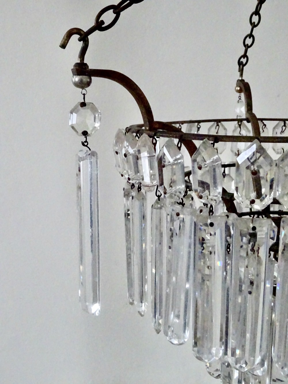 An Edwardian multi-tiered ceiling light featuring concentric rings of hanging cut crystal prisms suspended from a brass frame and chain. View VII