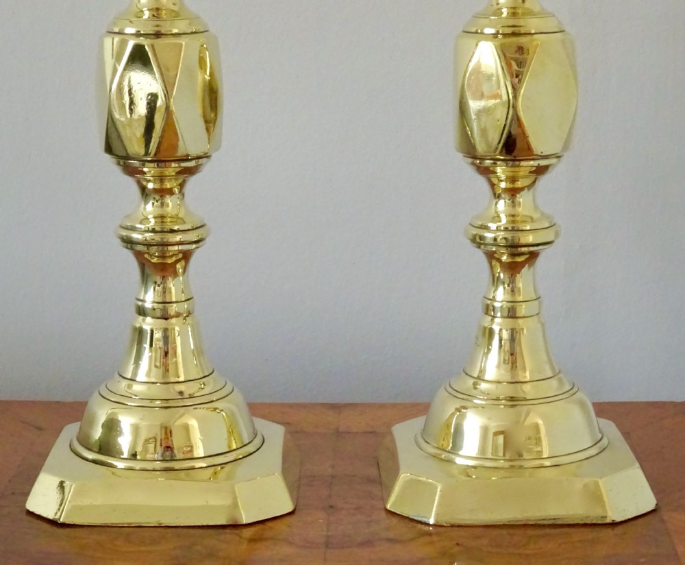 A pair of polished Victorian brass candlesticks with turned columns, faceted central knops, and square bases with cut corners. View II