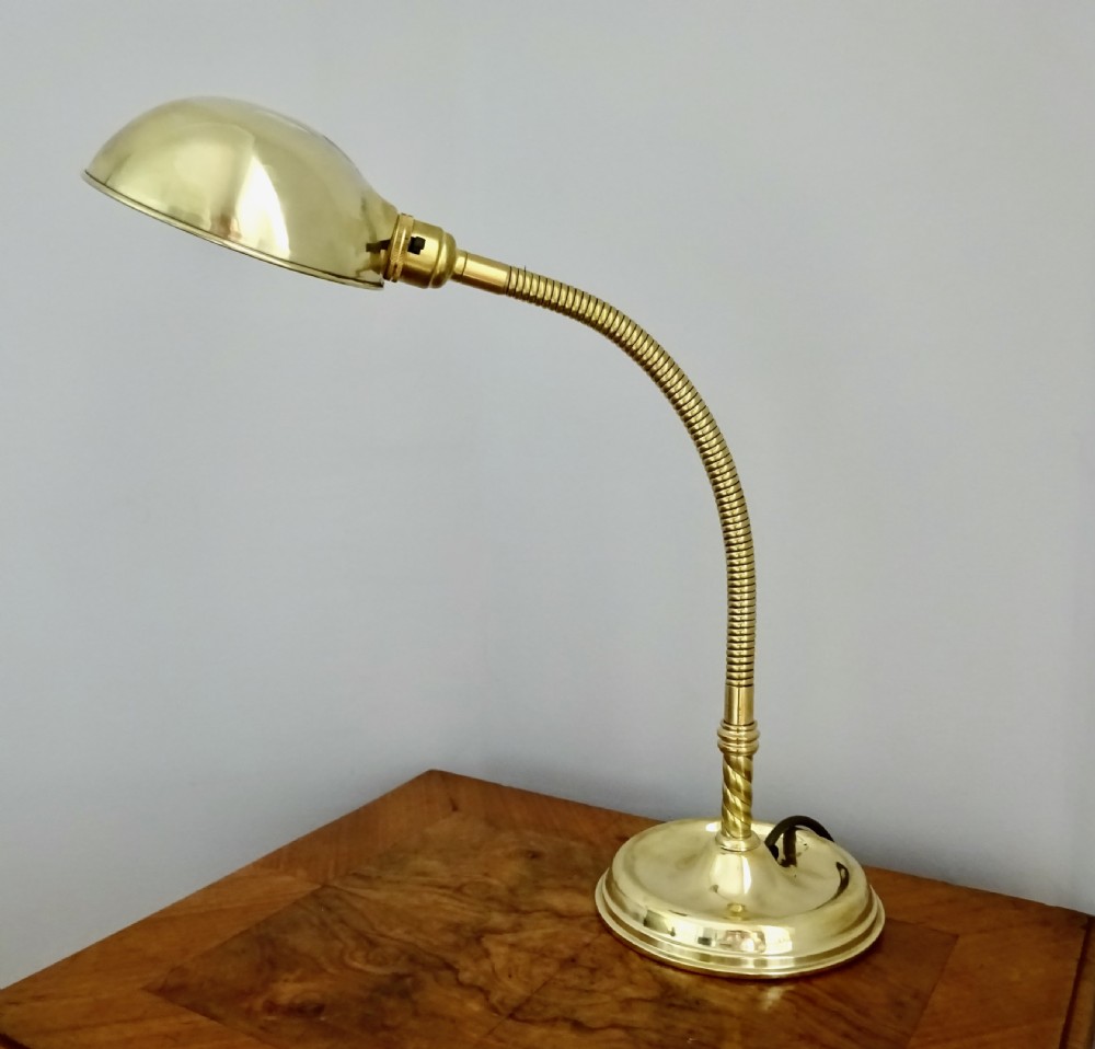 An Art Deco polished brass gooseneck desk lamp featuring an adjustable flexible arm, domed shade, and round stepped base. View VI