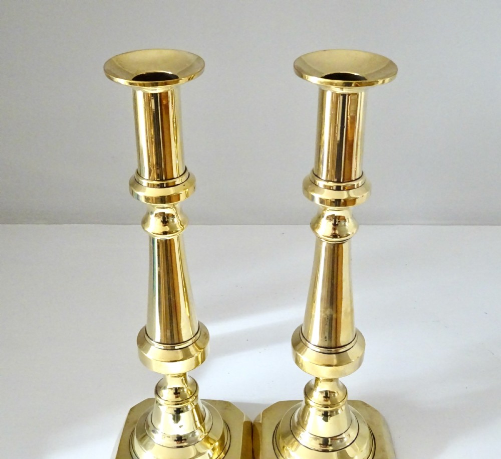 A pair of polished brass turned candlesticks featuring square bases and baluster columns. View II