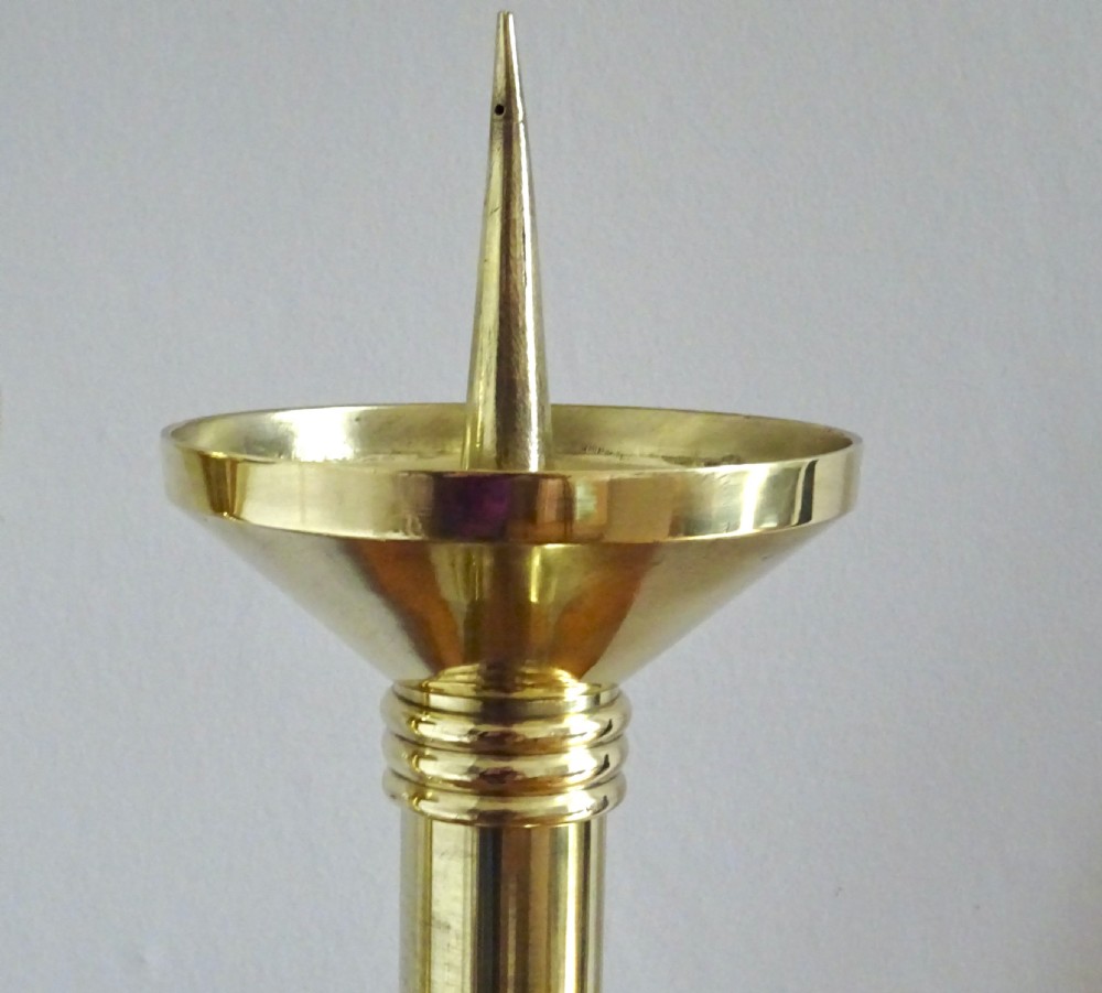 A pair of polished late Victorian brass pricket candlesticks featuring vertical spikes, flared drip pans, embossed stem knops, and tripod feet. View II