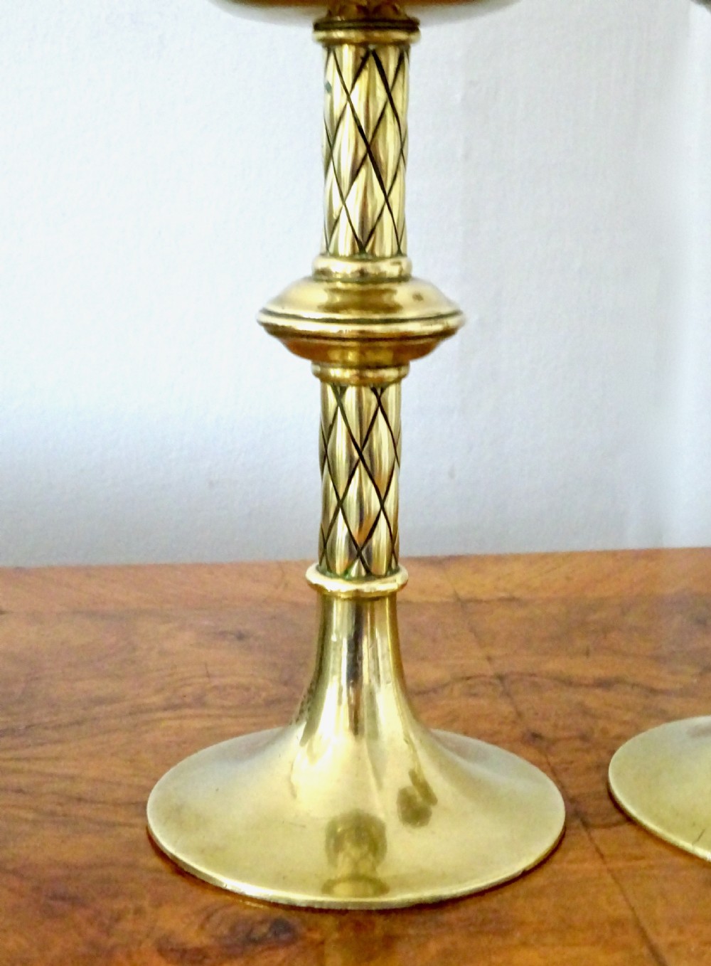 A pair of turned Victorian brass candlesticks featuring diamond-engraved stems, scalloped drip pans, and circular bases. View II