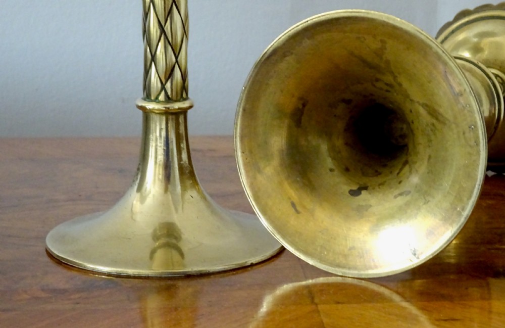 A pair of turned Victorian brass candlesticks featuring diamond-engraved stems, scalloped drip pans, and circular bases. View VI