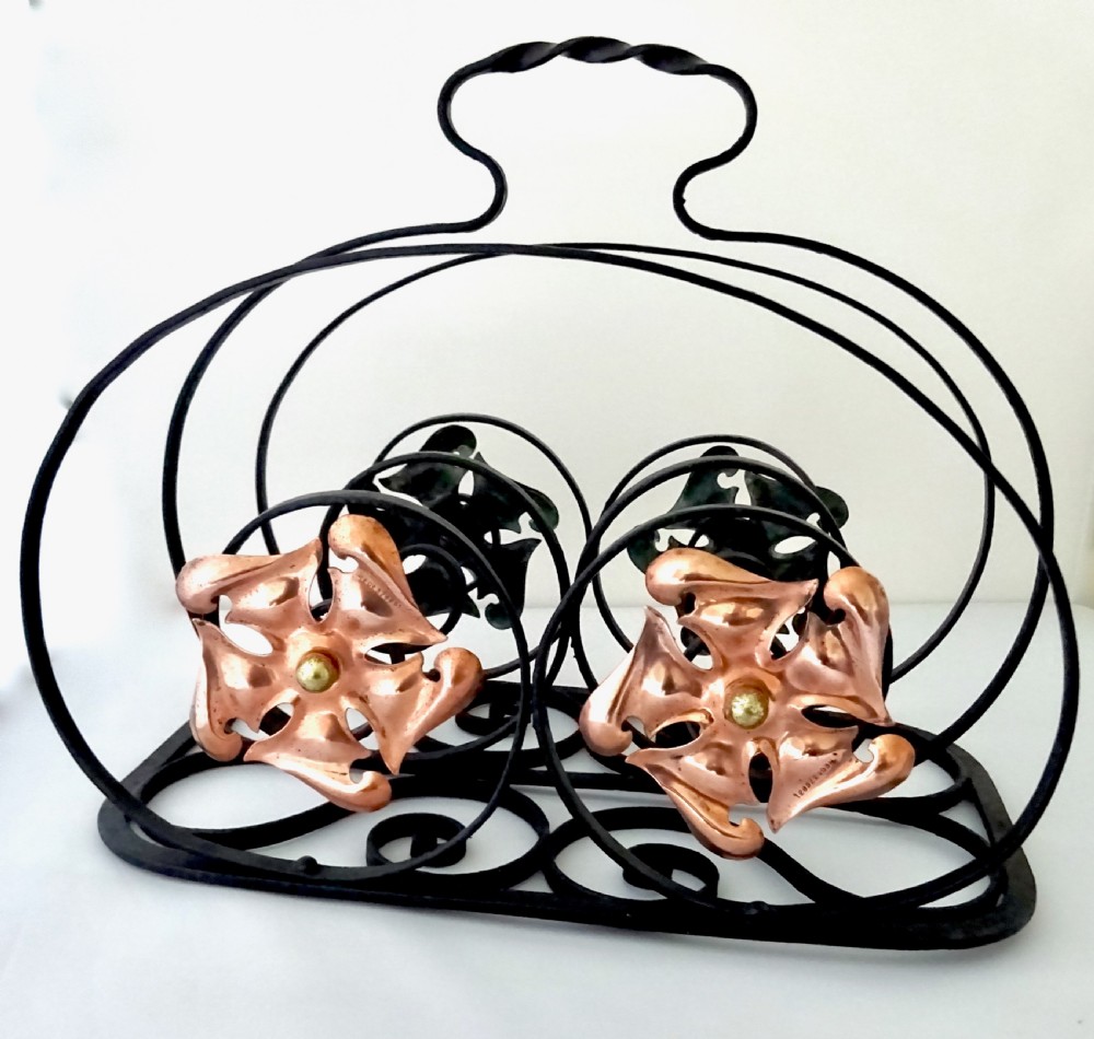 An Arts and Crafts wrought iron music rack featuring curved wire dividers, a twisted handle, and stamped copper flower motifs on the front. View V