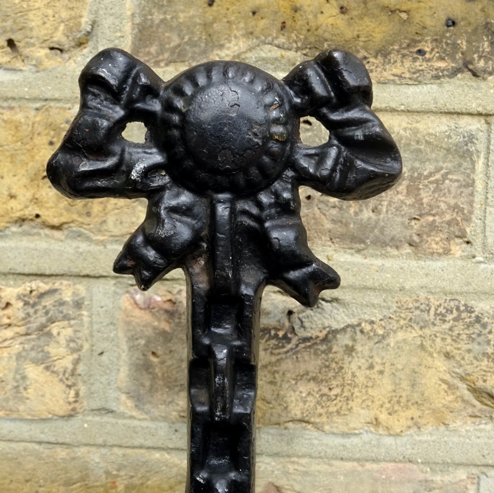 A Victorian black cast iron doorstop with a flared weighted base, central leaf column, and a ribbon bow motif top handle. View III