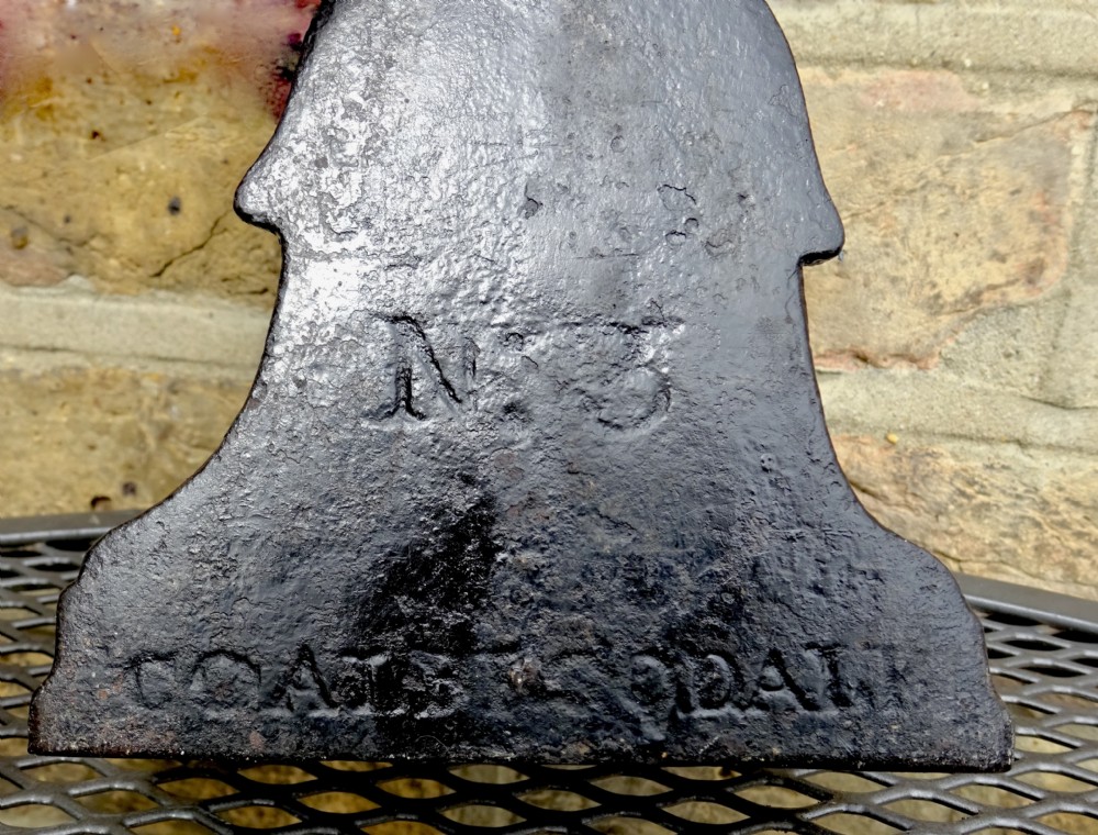 A Victorian black cast iron doorstop with a flared weighted base, central leaf column, and a ribbon bow motif top handle. View VI