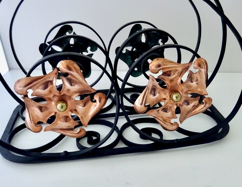 An Arts and Crafts wrought iron music rack featuring curved wire dividers, a twisted handle, and stamped copper flower motifs on the front. View II