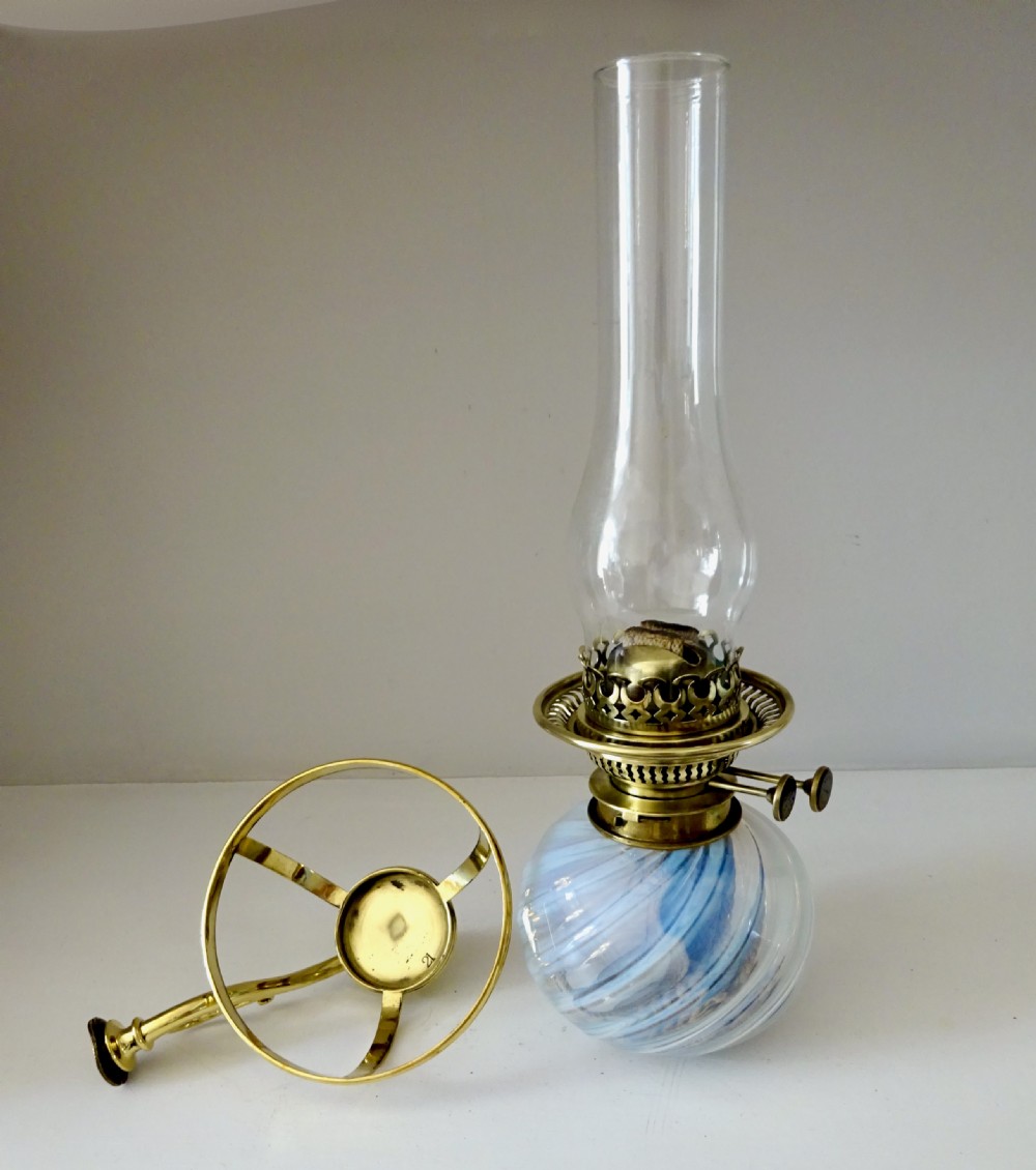 A Victorian brass wall-mounted oil lamp with a swirling blue glass reservoir held in a metal frame alongside a crimped blue glass shade. View III