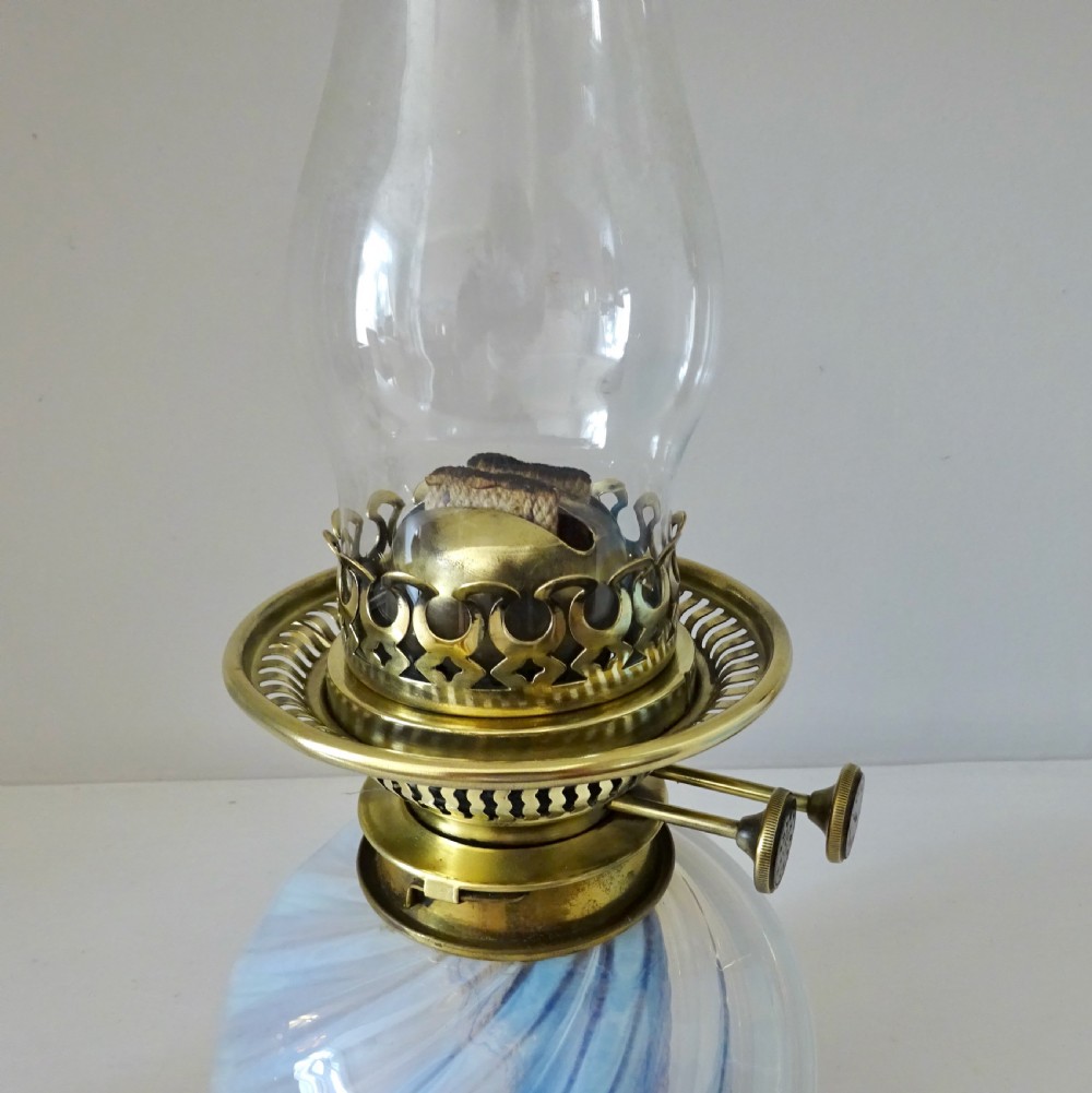 A Victorian brass wall-mounted oil lamp with a swirling blue glass reservoir held in a metal frame alongside a crimped blue glass shade. View IV
