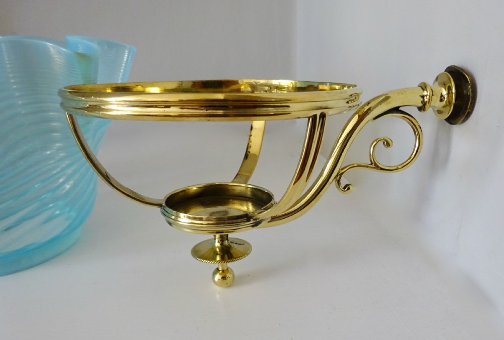A Victorian brass wall-mounted oil lamp with a swirling blue glass reservoir held in a metal frame alongside a crimped blue glass shade. View V
