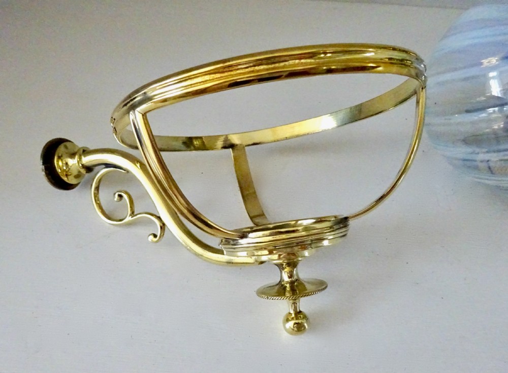 A Victorian brass wall-mounted oil lamp with a swirling blue glass reservoir held in a metal frame alongside a crimped blue glass shade. View VI