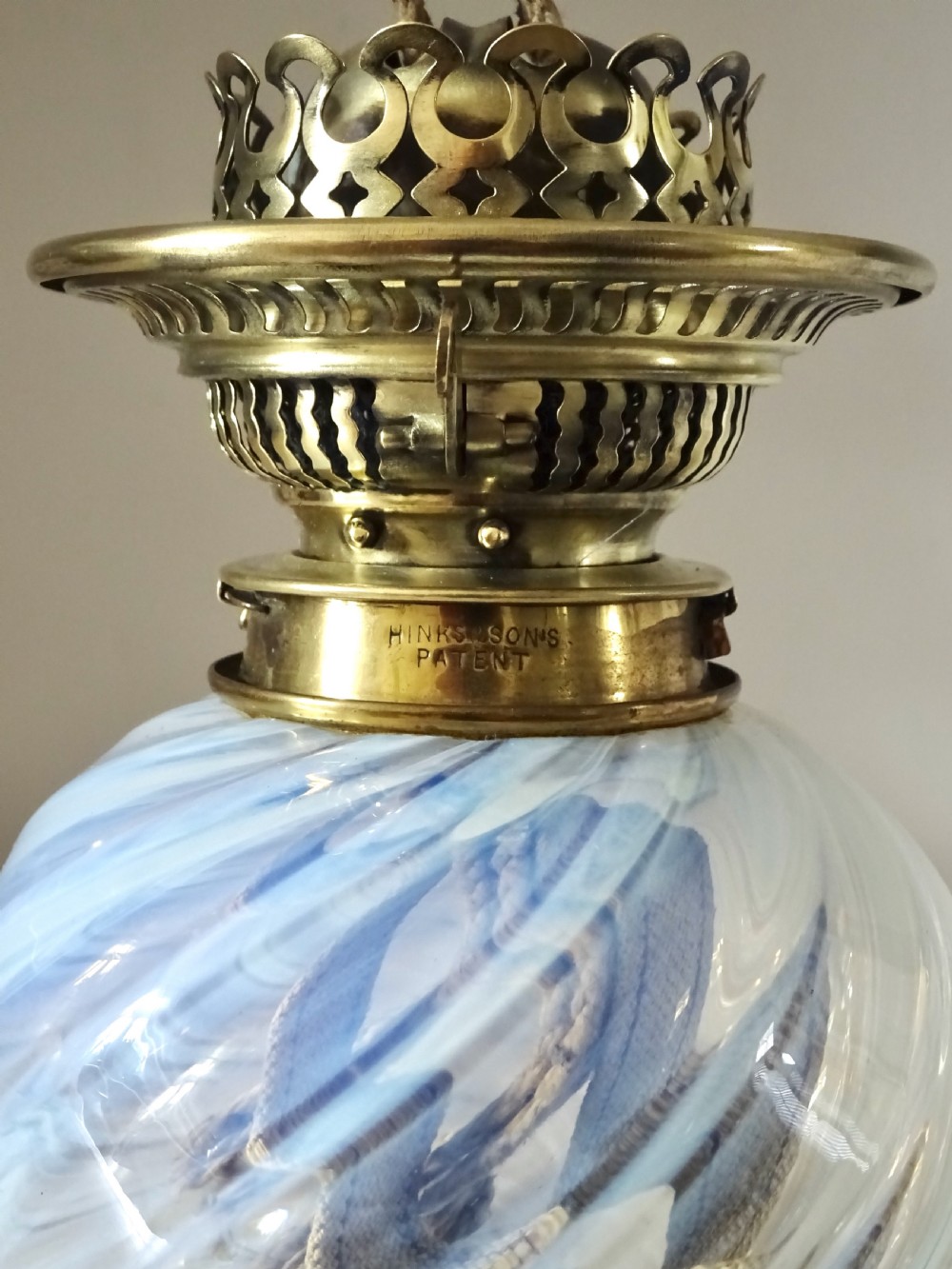 A Victorian brass wall-mounted oil lamp with a swirling blue glass reservoir held in a metal frame alongside a crimped blue glass shade. View XI