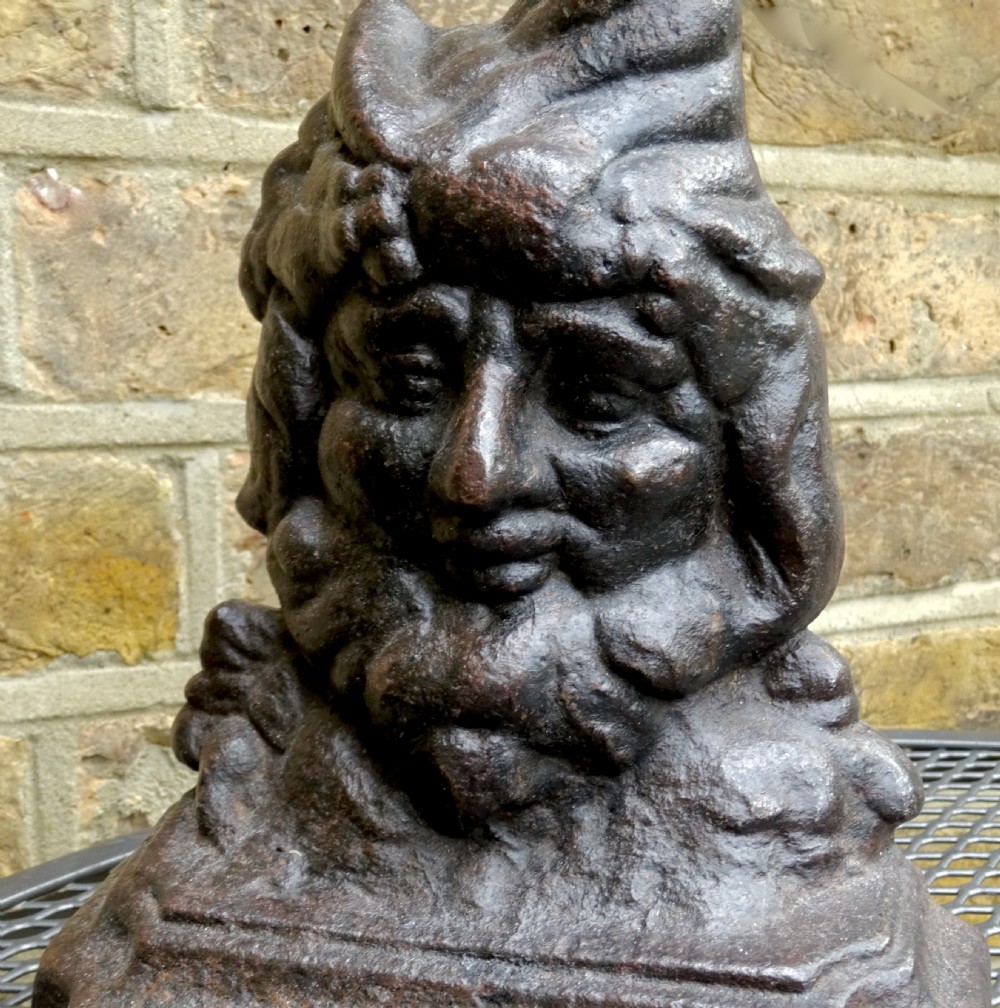 A Victorian cast iron doorstop featuring a molded figure of Punch with a tall curved cap forming a handle set on a stepped base. View V