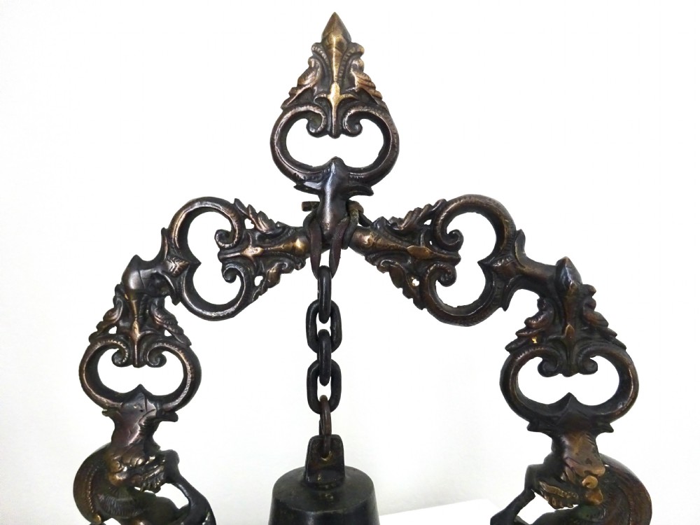 An ornate dark bronze table bell suspended by a chain from a cast arch frame with elephant bases and mythical figure uprights. View VI