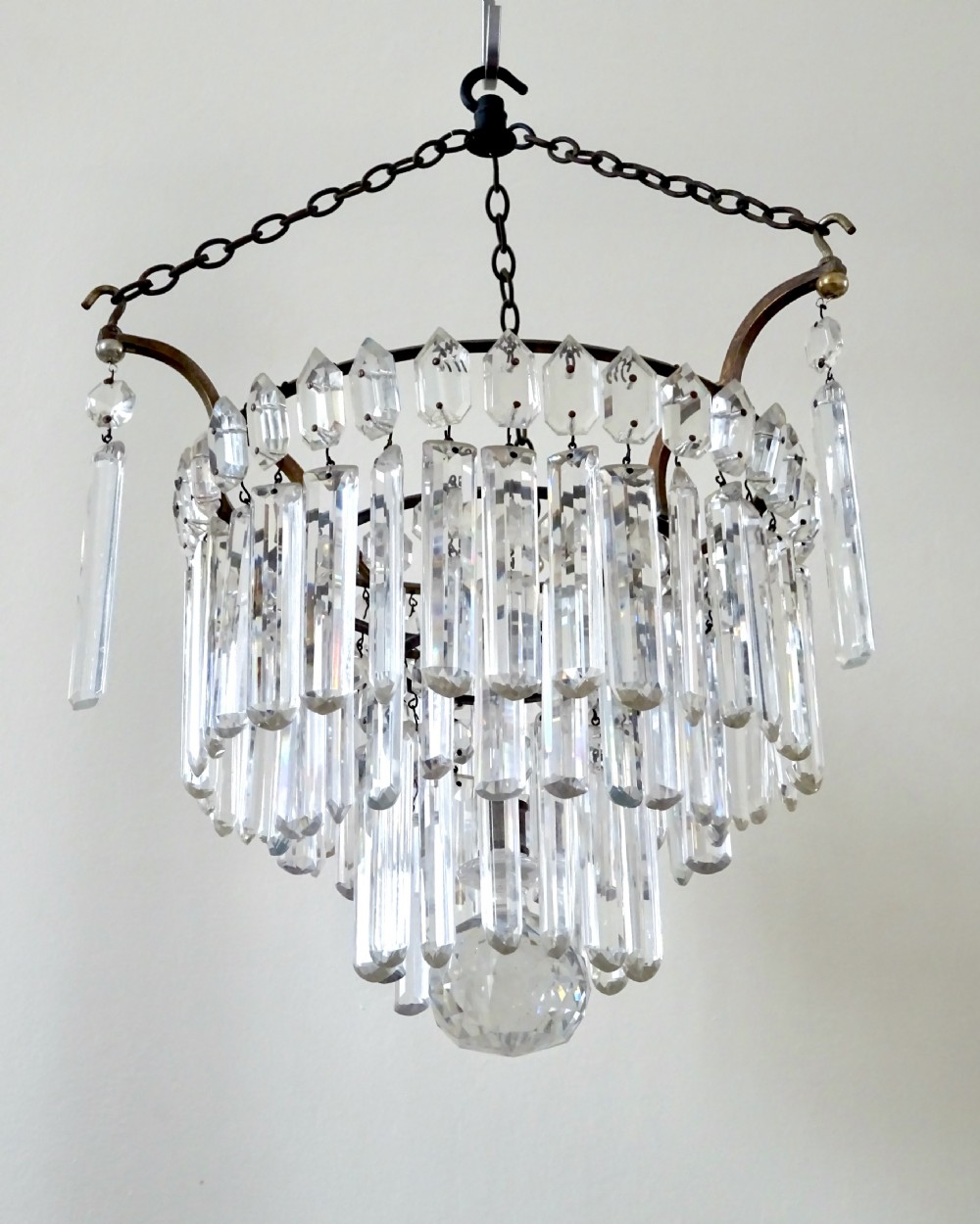 An Edwardian multi-tiered ceiling light featuring concentric rings of hanging cut crystal prisms suspended from a brass frame and chain.