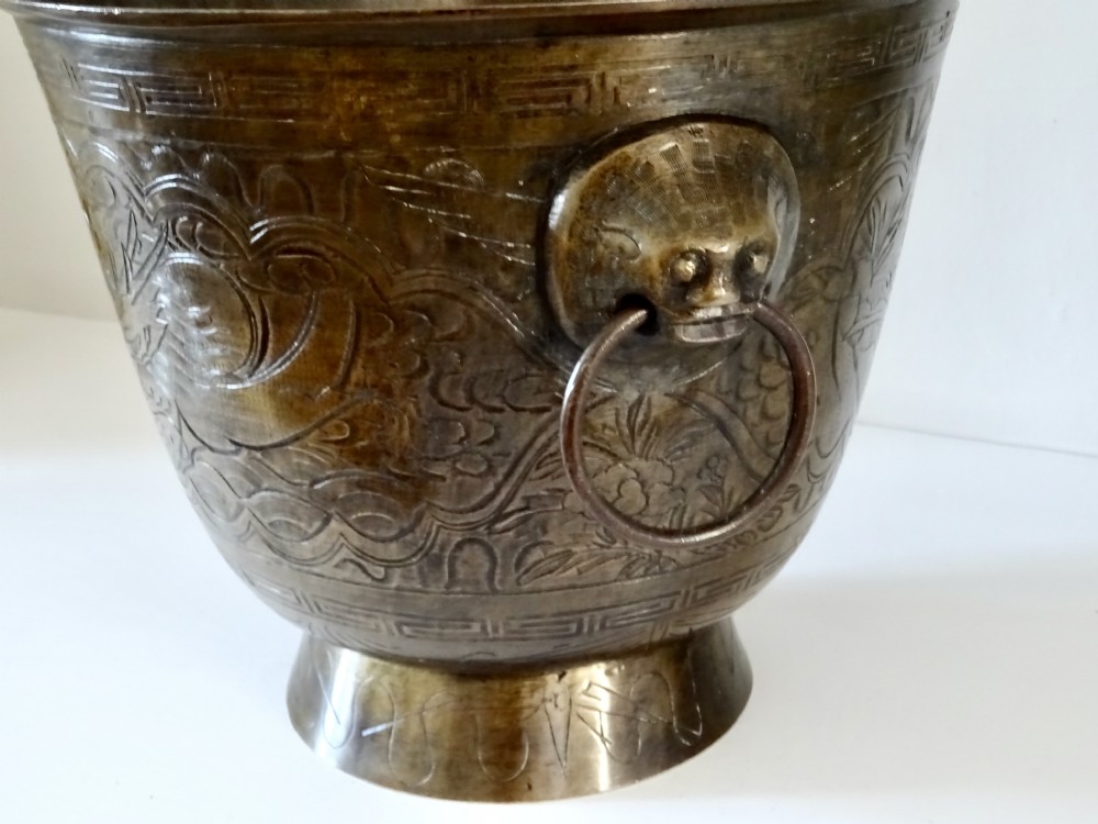A deep flared dark bronze jardiniere featuring mask drop-ring handles and intricate engraved pattern band on a pedestal base. View IV