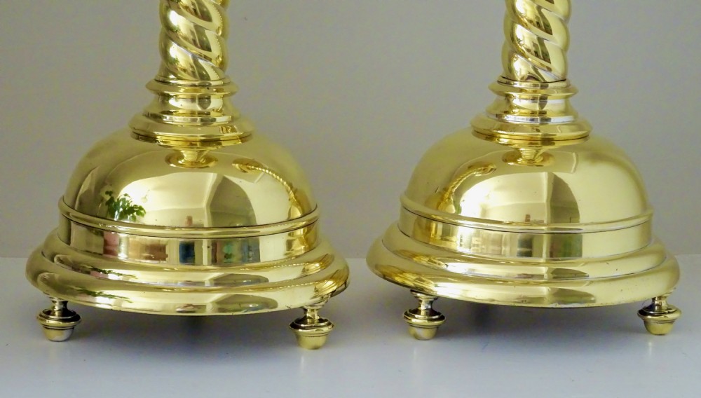 A pair of polished brass candlesticks with barley twist stems, broad drip pans, and domed bases set on small ball feet. View III