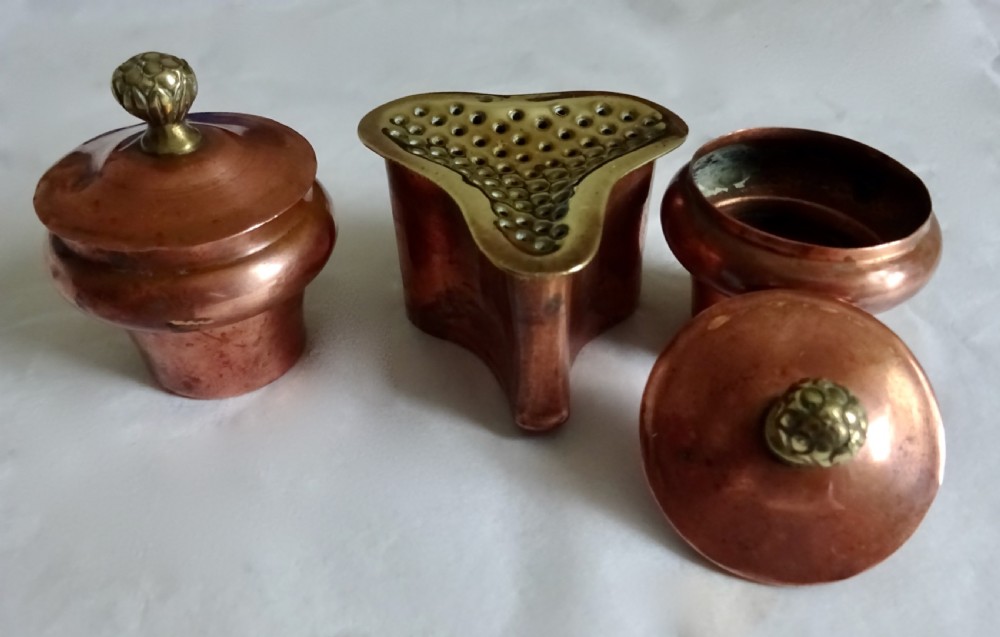 An antique copper and brass inkstand featuring a contoured backplate with a heraldic crest, brass swags, two capped inkwells, and brass hoof feet. View VIII