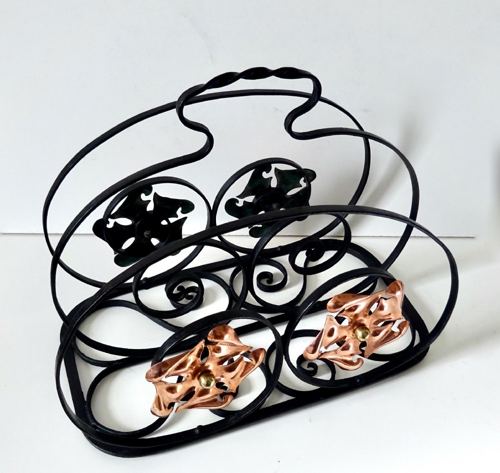 An Arts and Crafts wrought iron music rack featuring curved wire dividers, a twisted handle, and stamped copper flower motifs on the front. View III