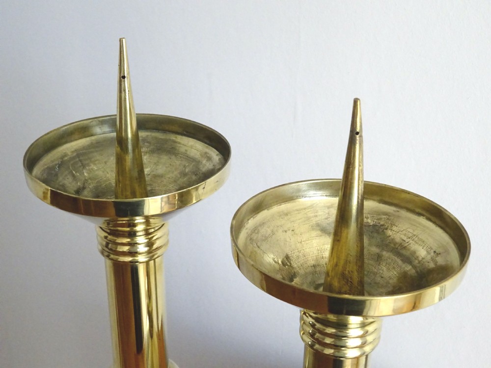 A pair of polished late Victorian brass pricket candlesticks featuring vertical spikes, flared drip pans, embossed stem knops, and tripod feet. View VI