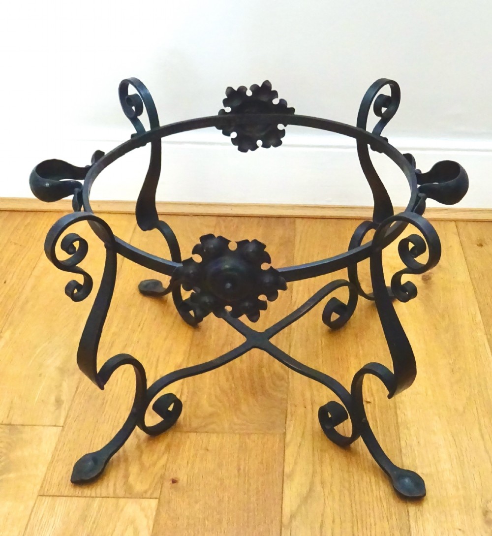 A large hammered copper bin with a domed lid fitted inside a black wrought iron stand with scrolled legs. View II