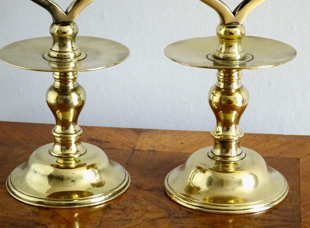 A pair of Victorian polished brass tavern candlesticks featuring turned baluster stems and integrated central hanging bells. View V