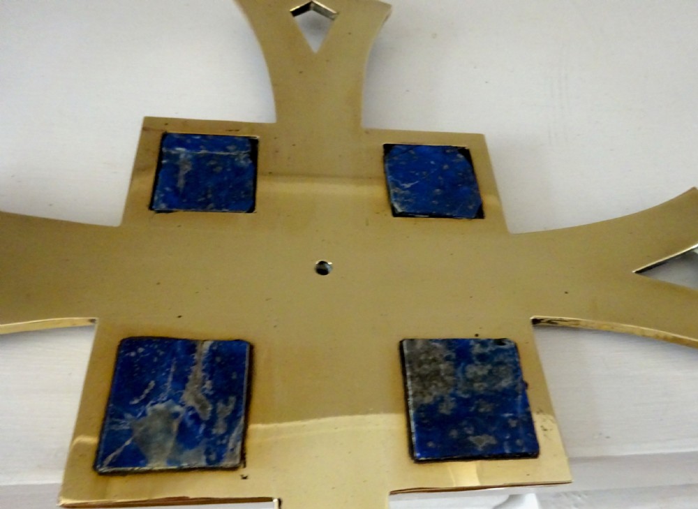 An Art Deco polished brass cross featuring flared arms with diamond cut-outs, ball finials, and four square lapis lazuli stone inlays at the centre. View V