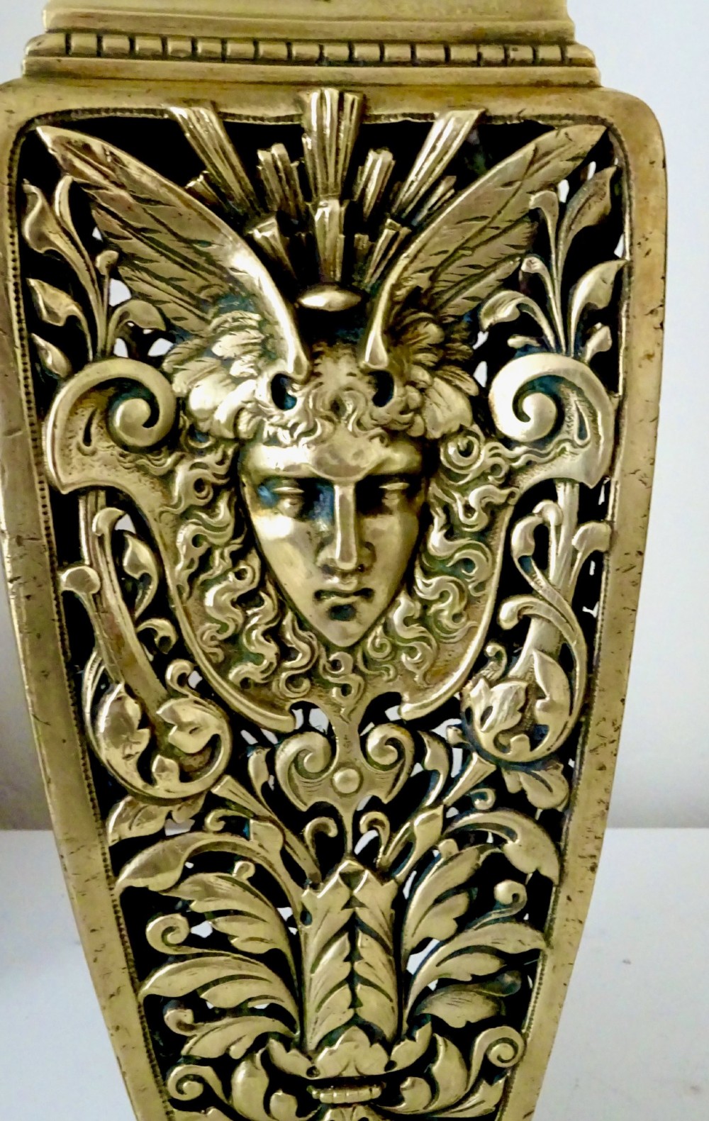 A pair of tall rectangular brass vases featuring pierced openwork scrolling foliage and central winged face motifs. View VI