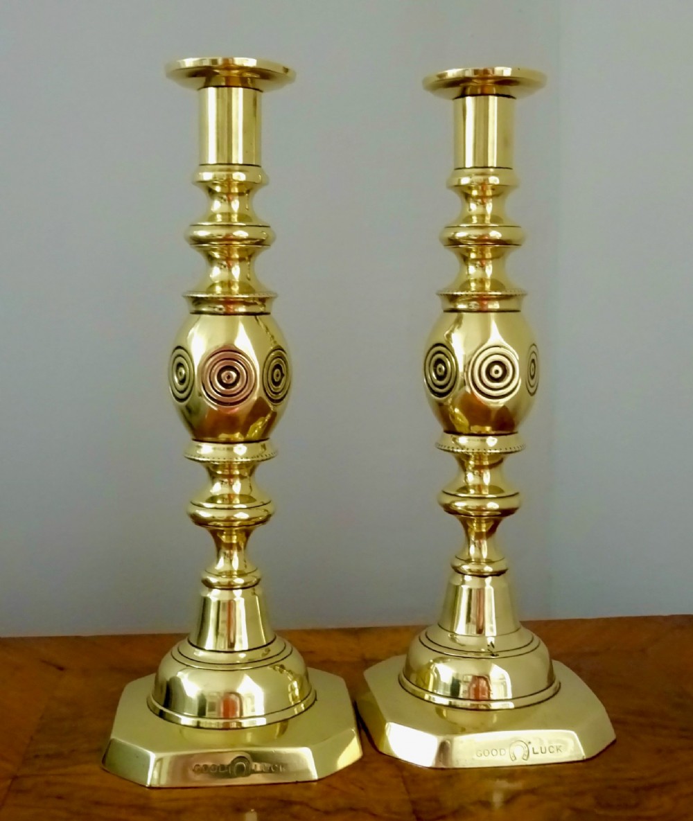 A pair of polished late Victorian cast brass candlesticks featuring knopped stems and octagonal bases stamped with the words Good Luck alongside a horseshoe motif. View II
