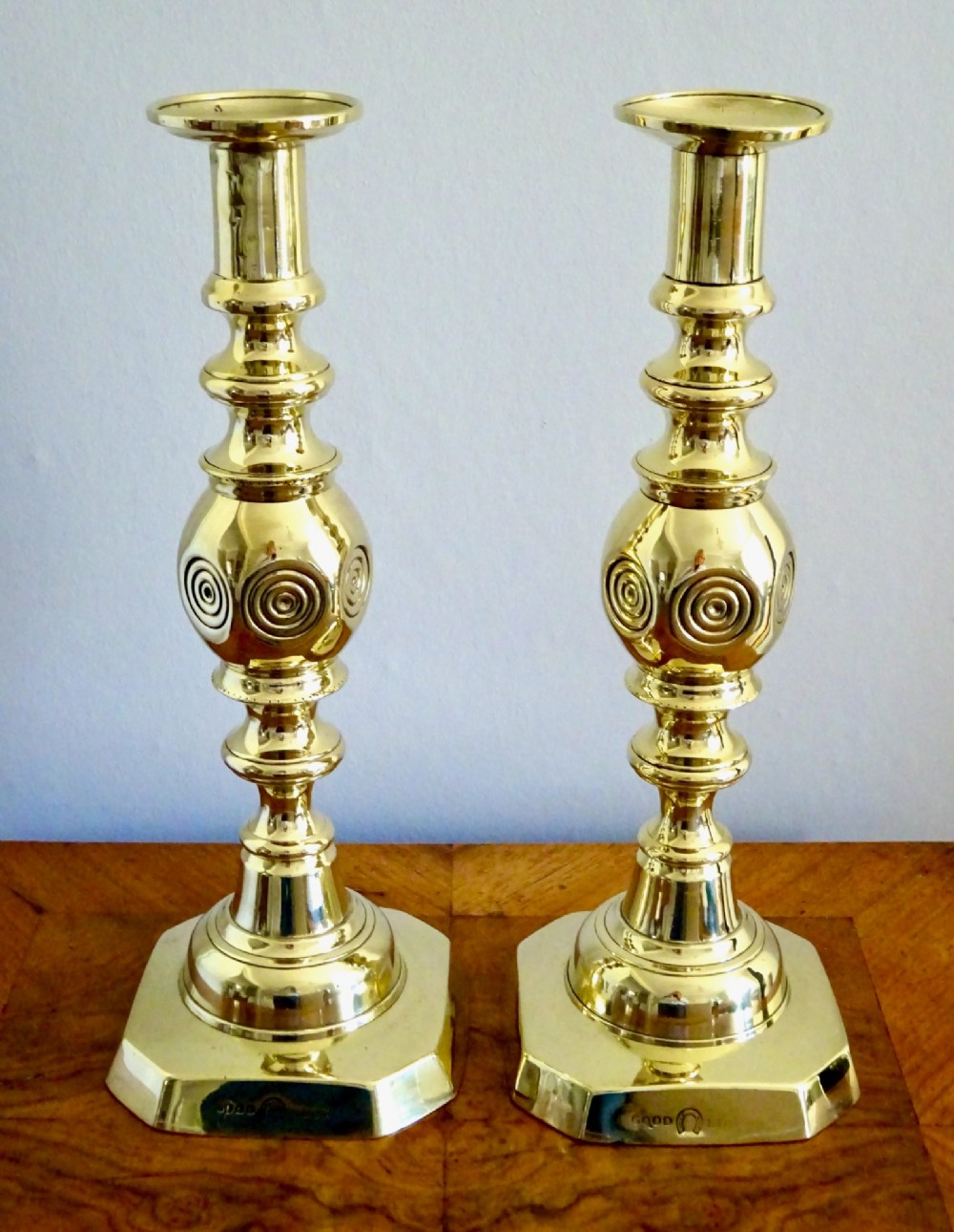 A pair of polished late Victorian cast brass candlesticks featuring knopped stems and octagonal bases stamped with the words Good Luck alongside a horseshoe motif. View V