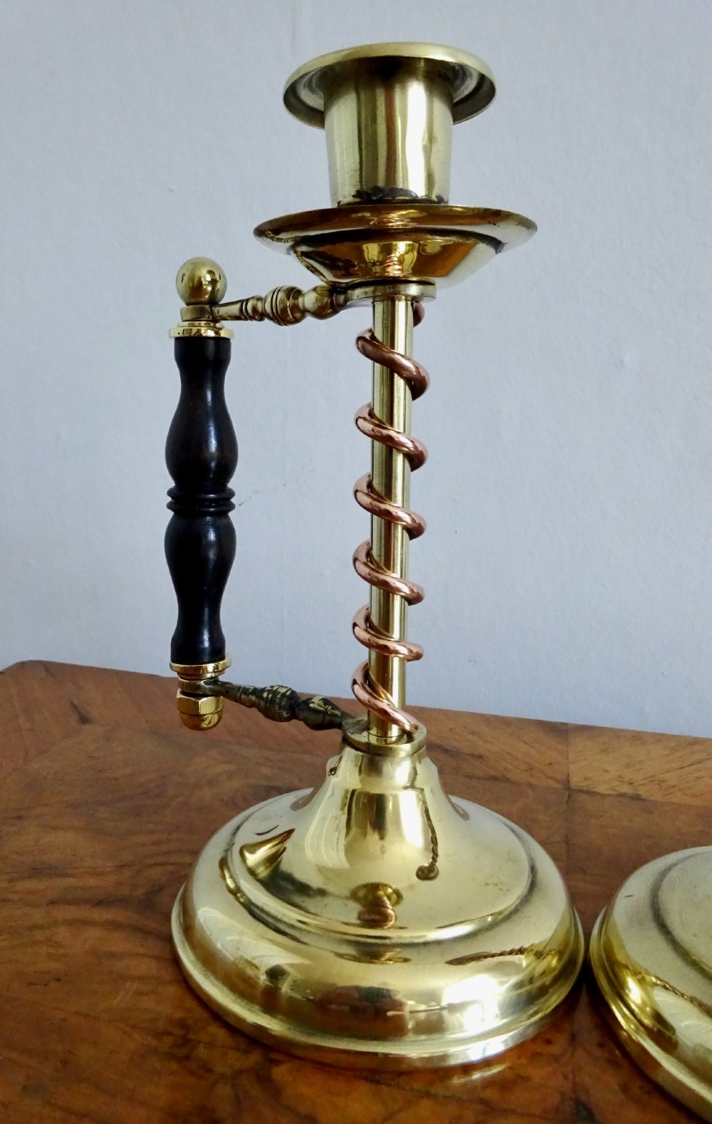 A pair of Edwardian Arts and Crafts brass candlesticks featuring spiral copper accents along the stems and turned dark wood side handles on circular brass bases. View III