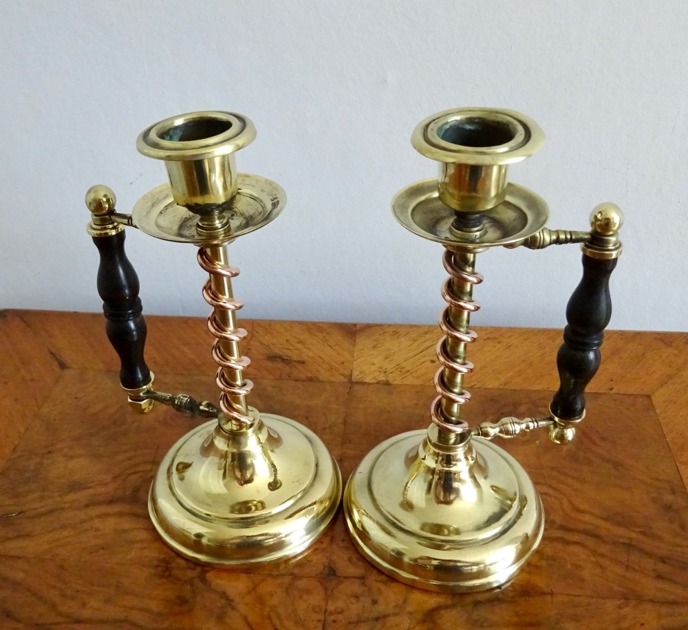 A pair of Edwardian Arts and Crafts brass candlesticks featuring spiral copper accents along the stems and turned dark wood side handles on circular brass bases. View VII