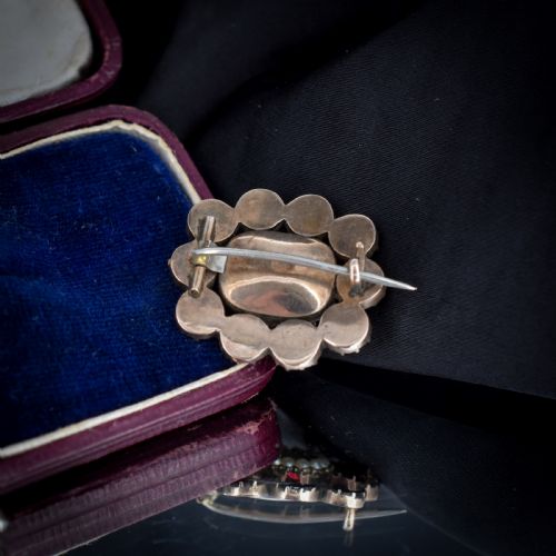 fig 2. A Georgian cluster brooch featuring flat-cut red garnets surrounding a halo of seed pearls and a central hairwork compartment set in gold.