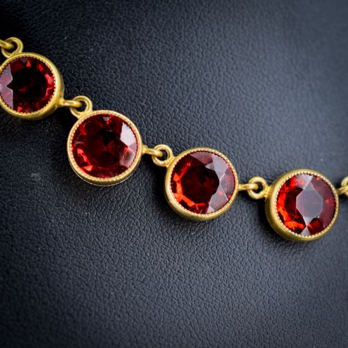 fig 2. An Edwardian gold gilt riviere necklace featuring round, bezel-set facetted red paste stones connected by fine metal links.