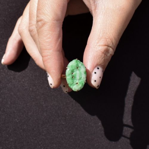 fig 1. An Art Deco oval ring showcasing a carved green jade panel mounted in a nine-carat yellow gold claw setting.