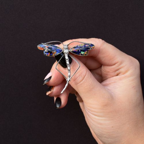 fig 1. An Art Deco sterling silver dragonfly brooch featuring a stylized segmented body and iridescent blue and orange wing inserts.