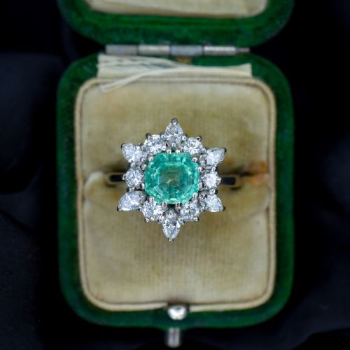 fig 2. A vintage gold cluster ring featuring a central octagonal green emerald surrounded by a snowflake halo of round and marquise diamonds.