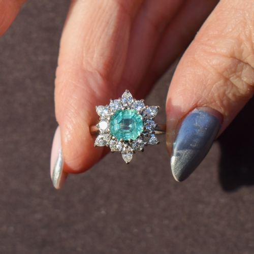 fig 3. A vintage gold cluster ring featuring a central octagonal green emerald surrounded by a snowflake halo of round and marquise diamonds.