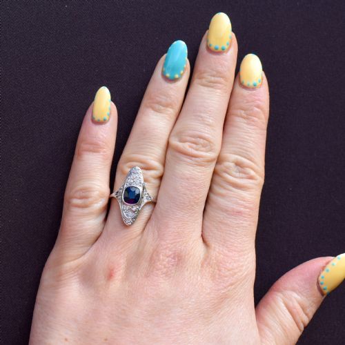 fig 1. An Art Deco platinum ring featuring a central blue sapphire framed by diamonds within an elongated navette-shaped setting.