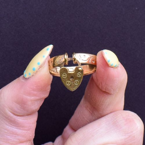 fig 1. An engraved 9ct yellow gold band featuring a dangling heart padlock charm.