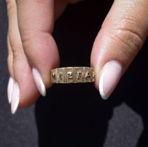 fig 1. An 18ct yellow gold Victorian Mizpah band ring featuring raised lettering set against a ribbed vertical background.