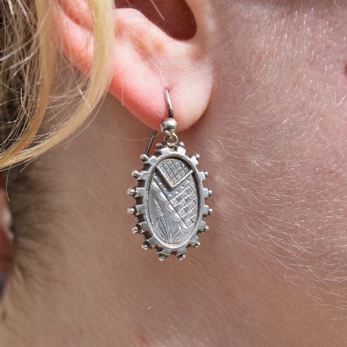 fig 1. A pair of oval sterling silver Victorian Aesthetic Movement drop earrings featuring engraved geometric and botanical designs with beaded borders.