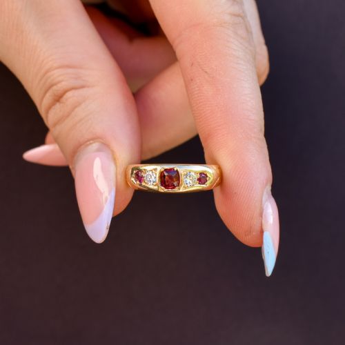 fig 1. An 18ct yellow gold band ring set with five cushion and round faceted red rubies, garnets, and diamonds in flush settings.