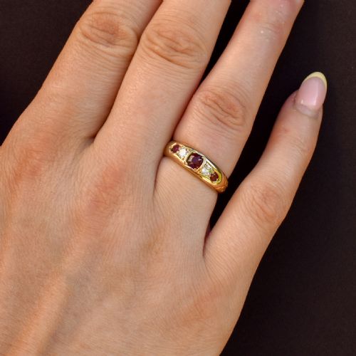 fig 3. An 18ct yellow gold band ring set with five cushion and round faceted red rubies, garnets, and diamonds in flush settings.